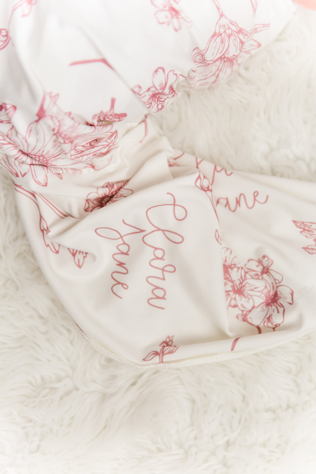 a close-up view of a white fabric with a floral pattern, featuring the name 'Cara' written in cursive script.