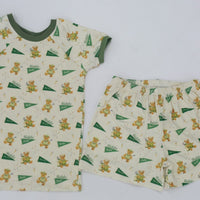A white t-shirt and shorts with a repeating pattern of green and yellow teddy bear designs.