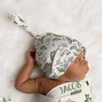 Newborn baby wrapped in a fish-themed swaddle and hat on a white fur background