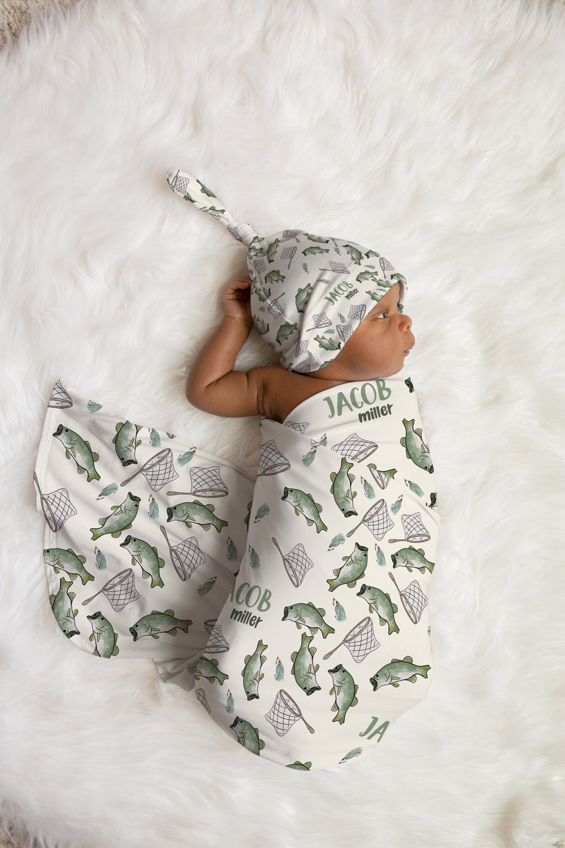 Newborn baby wrapped in a fish-themed swaddle and hat 