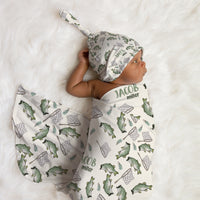 Newborn baby wrapped in a fish-themed swaddle and hat 