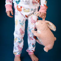 A child wearing her personalized chicken pajamas and holding her stuffed animal. 