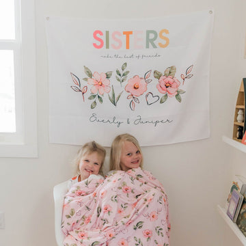 Sisters tapestry, personalized name banner, pink floral wall decor, kids room sign, girls' bedroom decor, playroom decoration, sisterly love, custom wall art, whimsical charm, high-quality materials