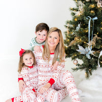 Mom and kids wearing matching striped Christmas pajamas in front of Christmas tree.