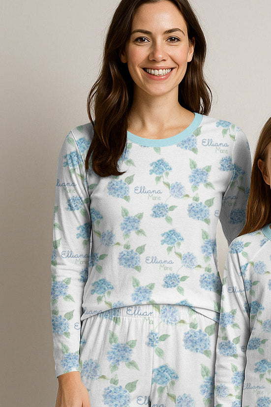 Woman and child wearing matching pajamas with a blue and white floral pattern on a plain background