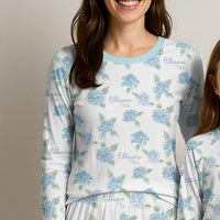 Woman and child wearing matching pajamas with a blue and white floral pattern on a plain background