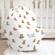 Baby seat cover with teddy bear pattern and baby's name in a nursery setting.