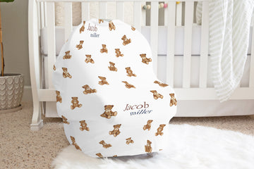 Baby seat cover with teddy bear pattern and baby's name in a nursery setting.