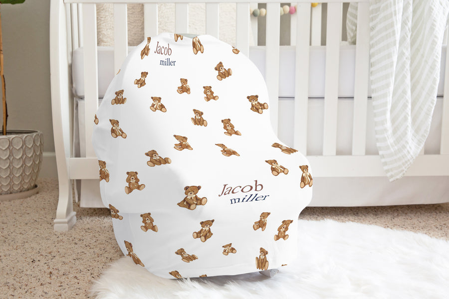 Baby seat cover with teddy bear pattern and baby's name in a nursery setting.