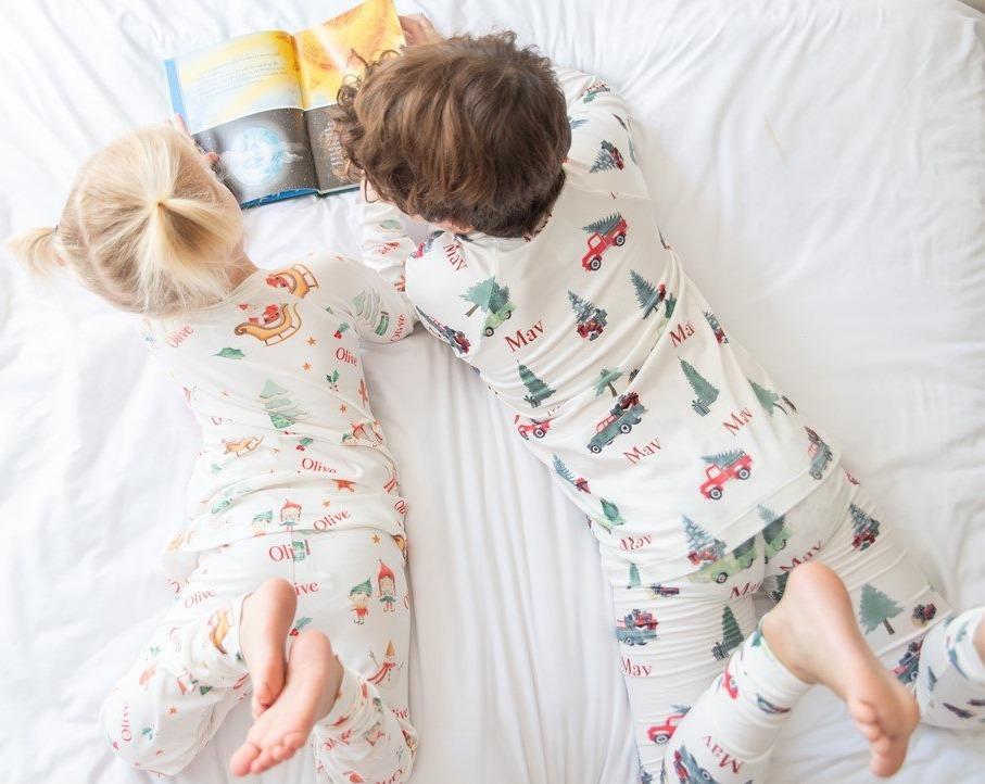 Two kids reading a book together while wearing matching Gingerbread Christmas Pajamas. 