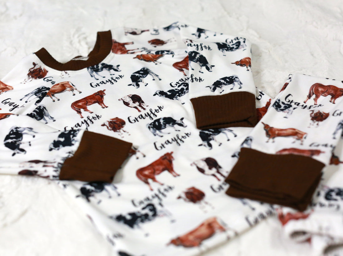 Our personalized cow pajamas folded nicely on a bed. The design has brown cows with white spots and black cows with spot spots. 