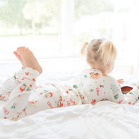 Little girl laying on the bed wearing her new Gingerbread Christmas Pajamas. 